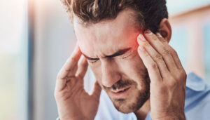 Man suffering from headaches. Holding his temporals and squinting his eyes